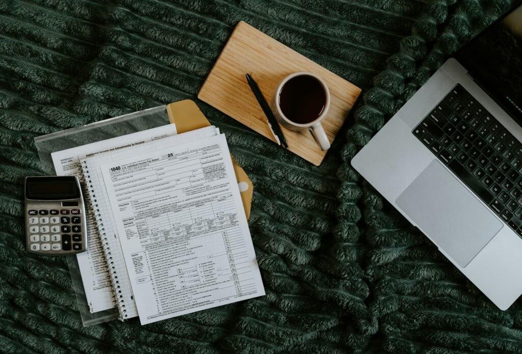 Laptop, papers and calculator on a table while reviewing spending for a budget