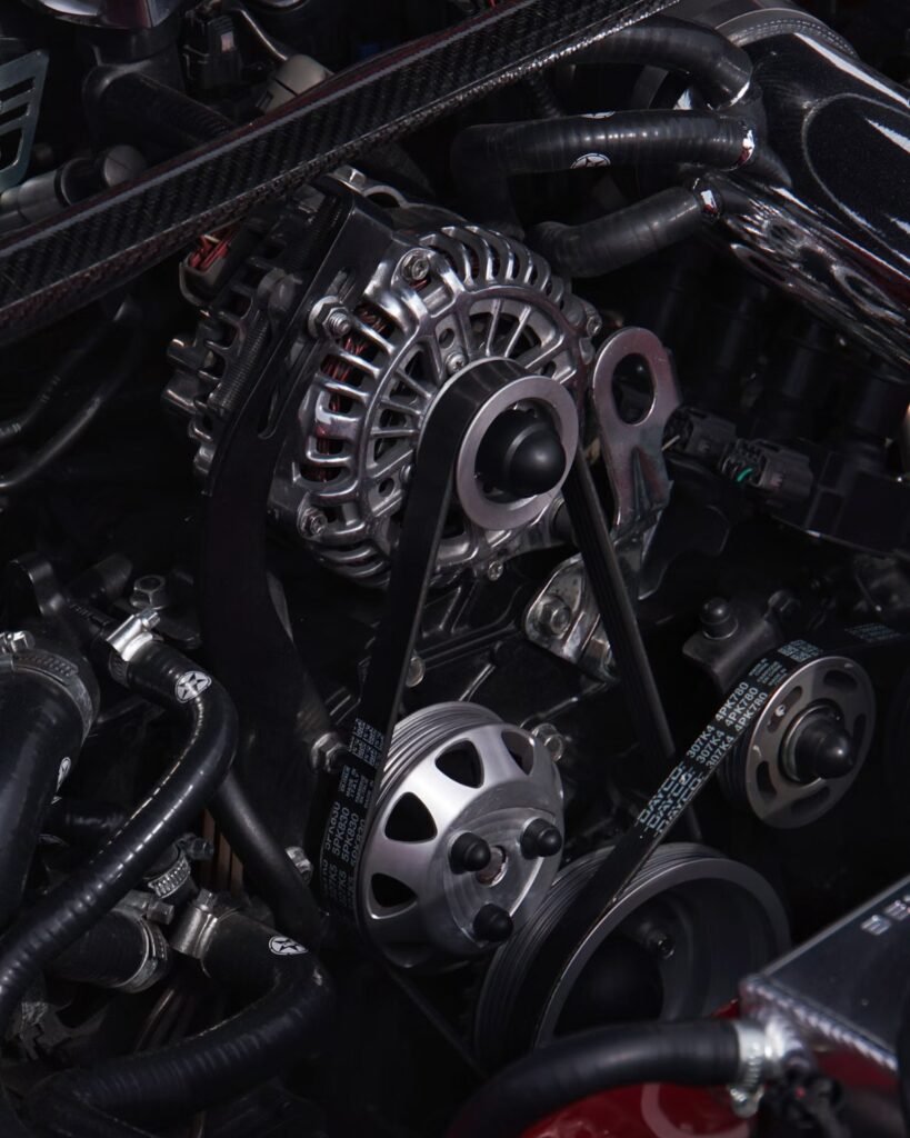 Close-up of a car engine bay showing the alternator area and drive belt