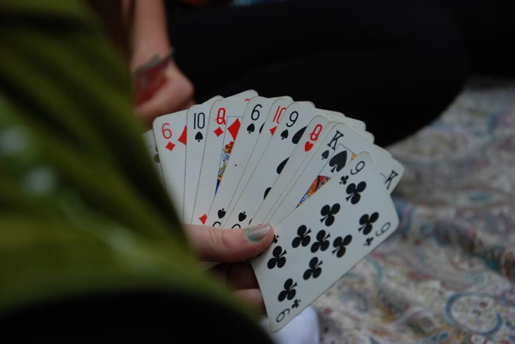 12 Best 2 Player Card Games for Couples (Easy Rules for Date Night) 4 Person holding a fanned hand of playing cards during a card game for two