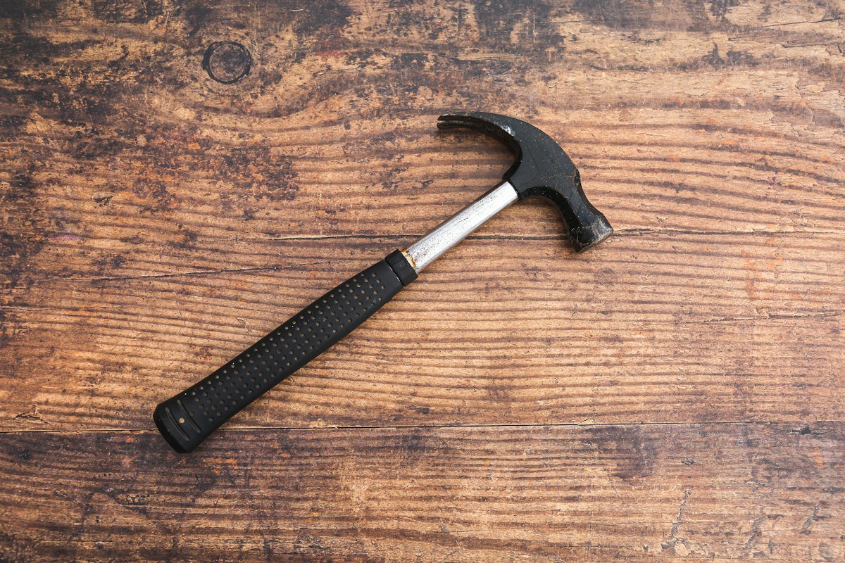 Hammer with a black handle on a wooden table