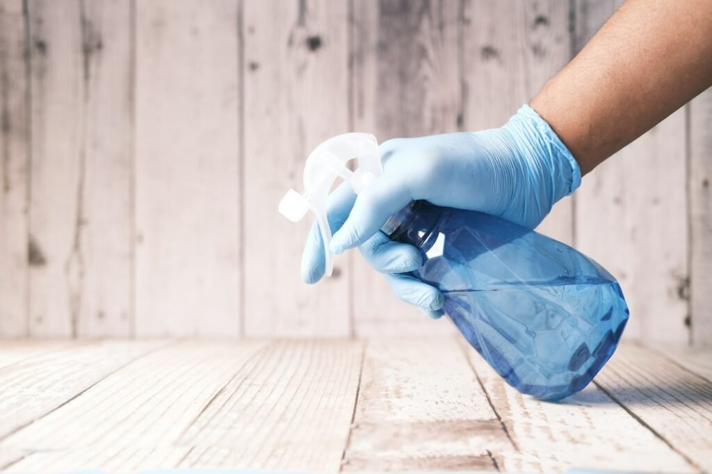 How to Clean a Fan: Ceiling, Box, Pedestal and Tower Fans 2 Gloved hand holding a spray bottle with mild cleaning solution for wiping fan parts