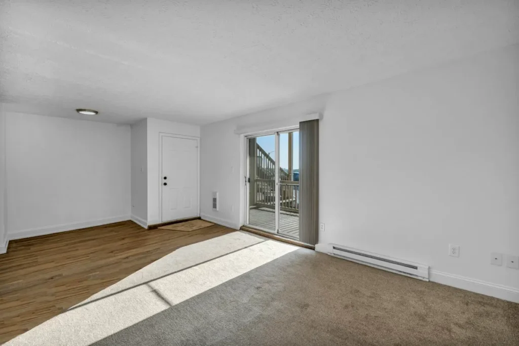 Clean white baseboards along a wood floor in a bright, empty room
