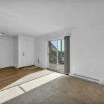 Clean white baseboards along a wood floor in a bright, empty room