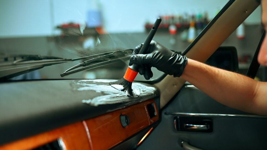 Detailer wiping down a car dashboard and interior surfaces