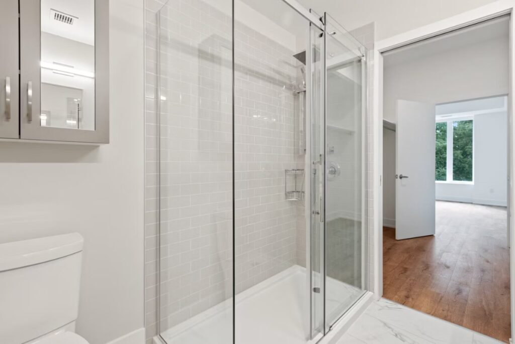 Clear glass shower door in a bright white bathroom