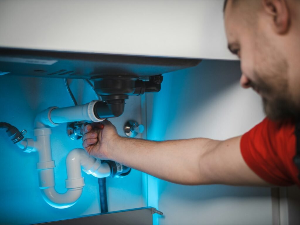 Person turning the water supply valve behind a toilet before a repair