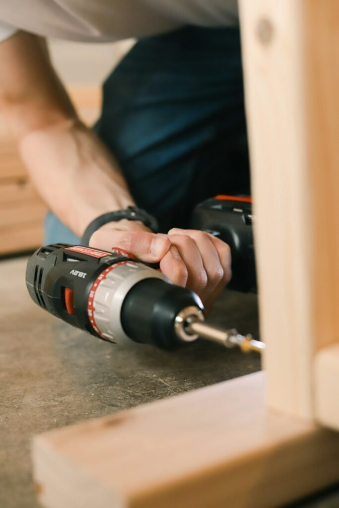 Person holding a cordless drill used to drive screws and fix creaky floorboards