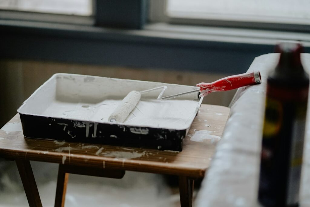Paint roller resting in a tray of white paint, ready for a freshly cleaned wall