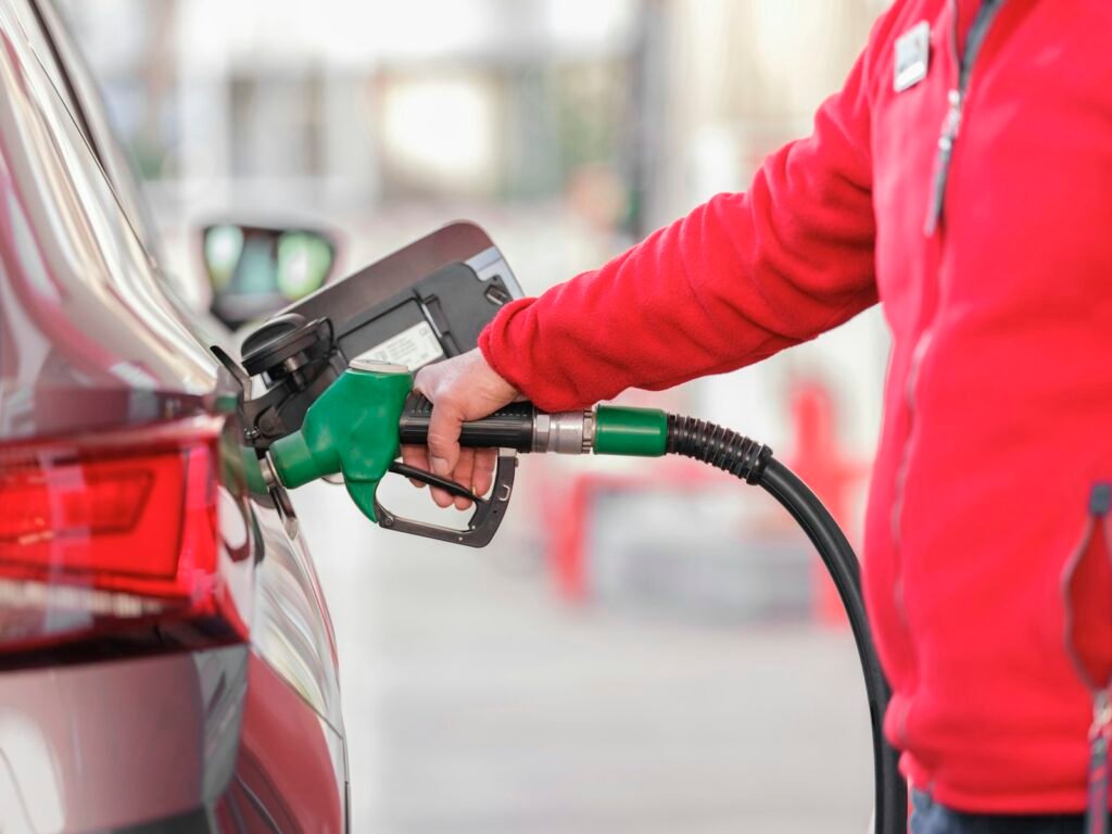 Driver filling up a car at a gas station while trying to save money on gas