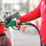 Driver filling up a car at a gas station while trying to save money on gas