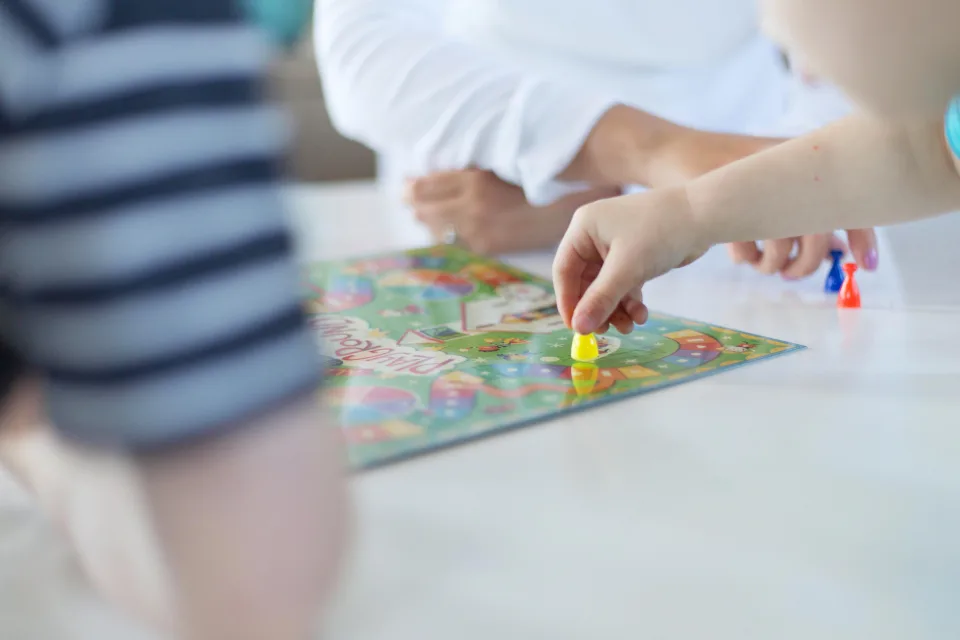 Child moving a game piece on a board game for screen-free learning