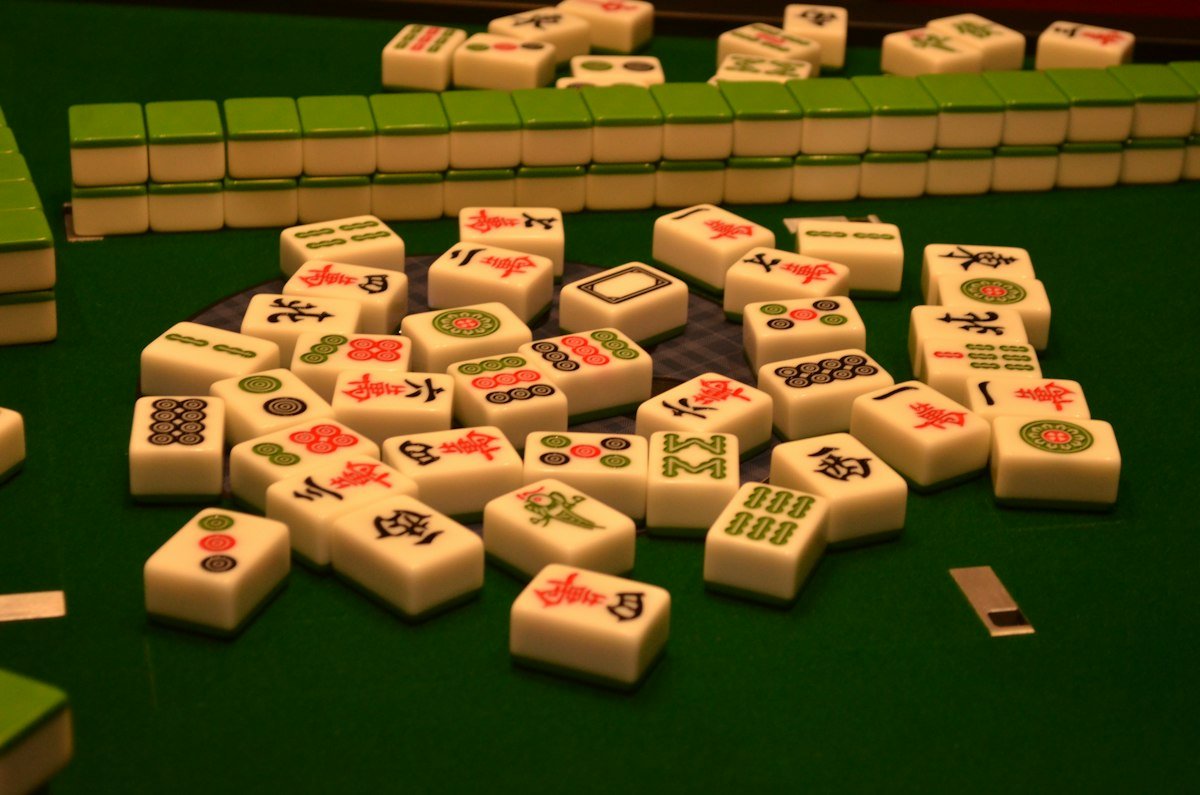 How to Play Mahjong: Rules, Tiles, and Tips for Beginners 4 Mahjong tiles on a green felt table with the wall built in the center