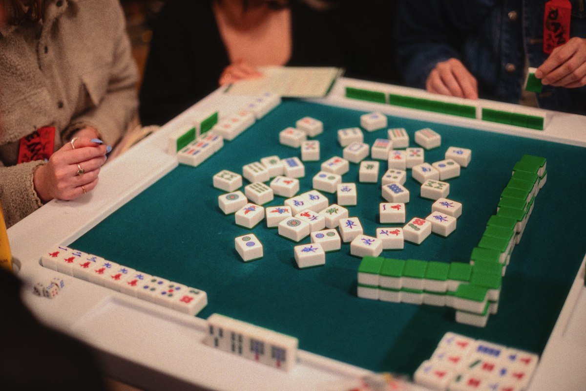 How to Play Mahjong: Rules, Tiles, and Tips for Beginners 5 People playing a hand of mahjong at a table