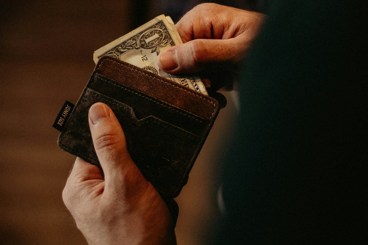 Person putting a dollar bill into a wallet