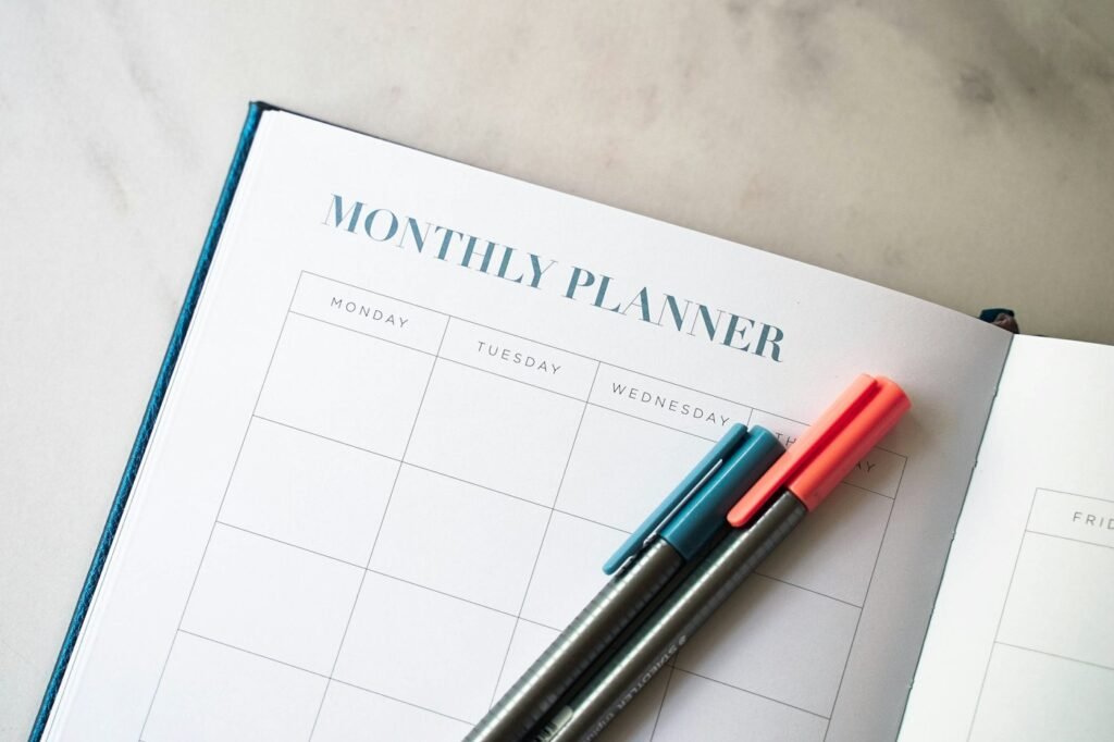 Monthly budget planner with two pens used to track expenses by category
