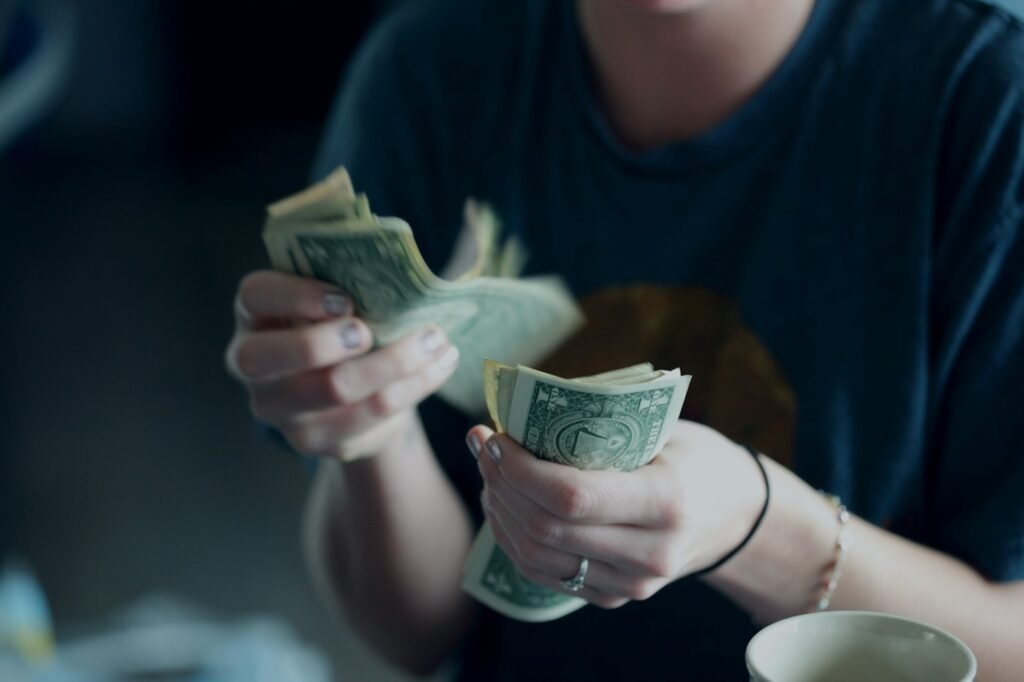 Person counting dollar bills to fill cash envelopes for a zero-based budget