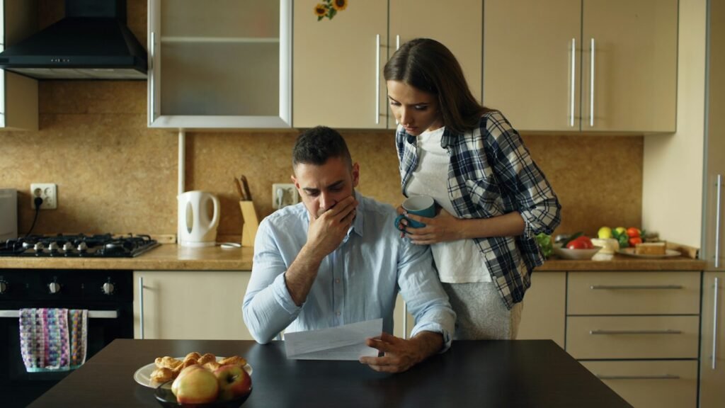 Couple sitting at a kitchen table reviewing bills and planning their budget together